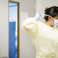 Bildet viser Leny Abila som tar på seg munnbind.