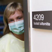 Kvinne i beskyttelsesytstyr utenfor isolat.